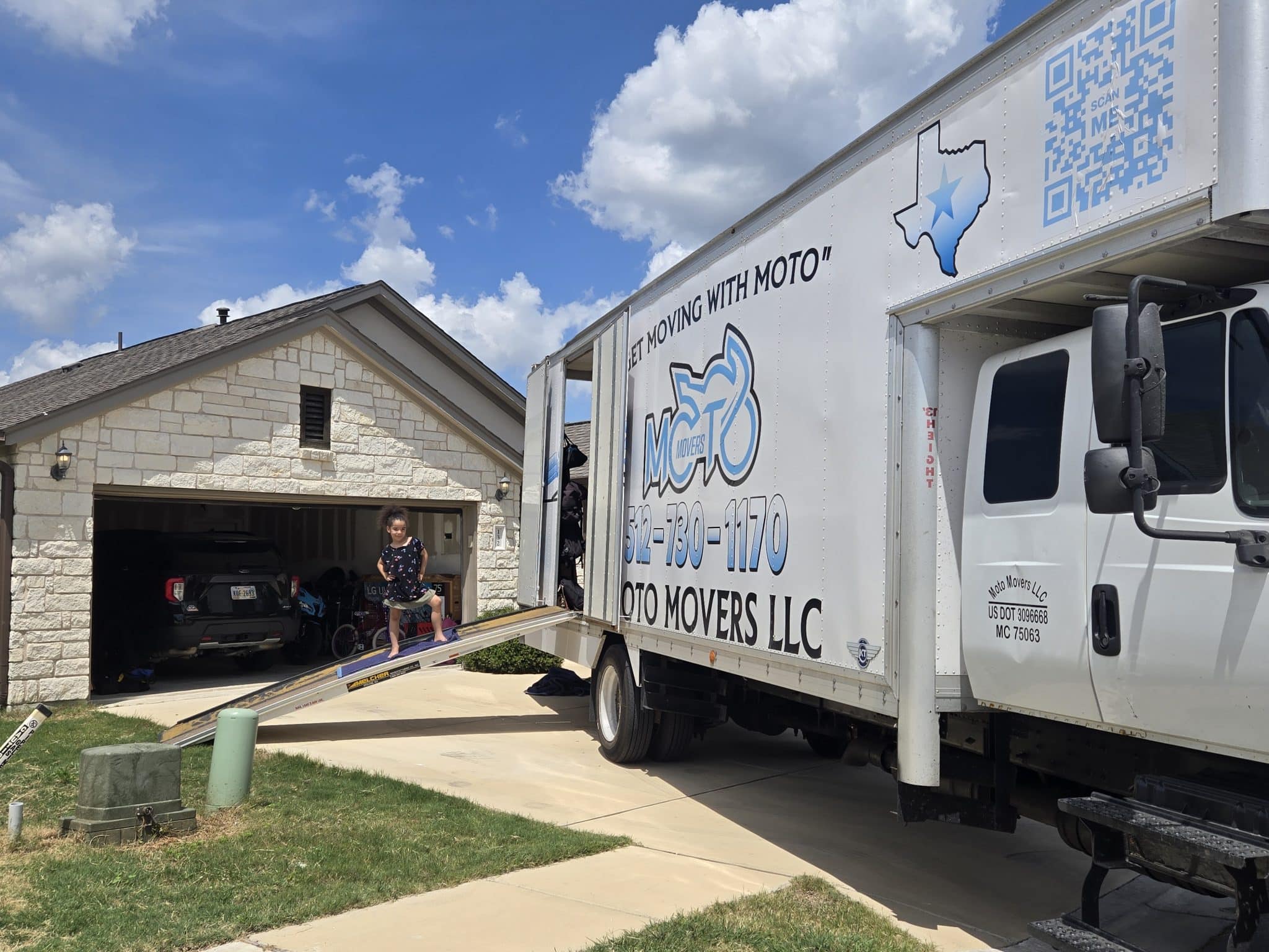 Child moves belongings into home using Moto Movers truck ramp.