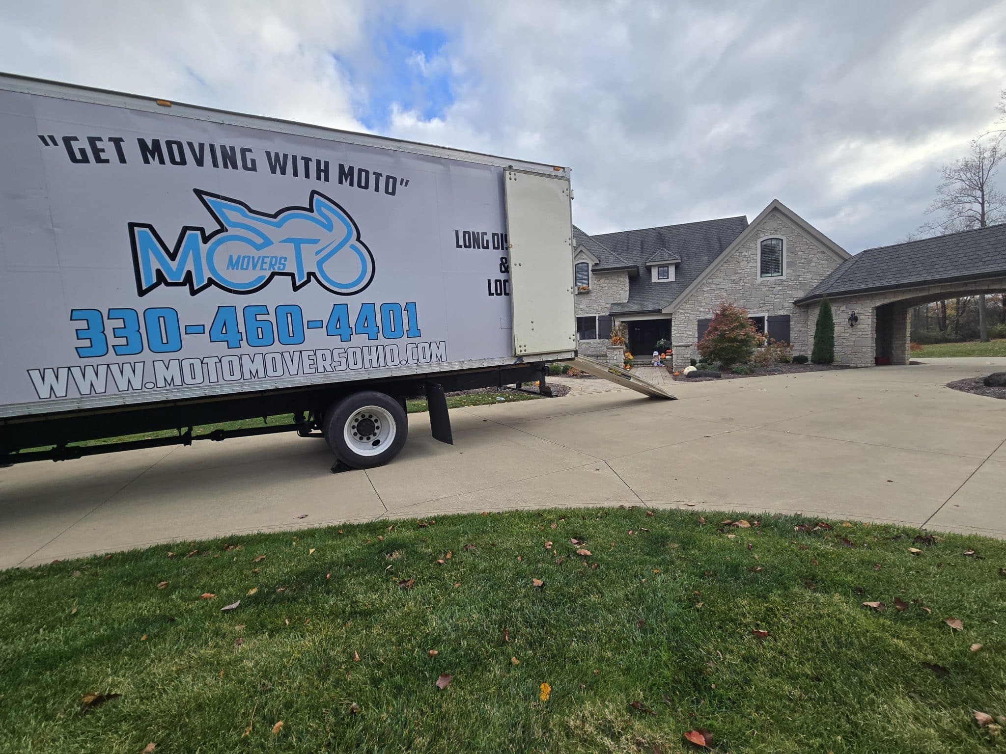 Moving truck from Moto Movers parked in front of a suburban house.