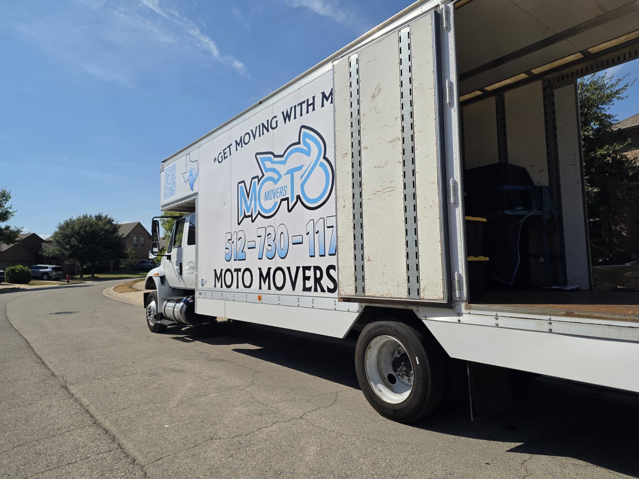 Moto Movers at Round Rock, TX residence Moving truck parked on a suburban street of Round Rock, Texas. Labeled Moto Movers with open cargo area.