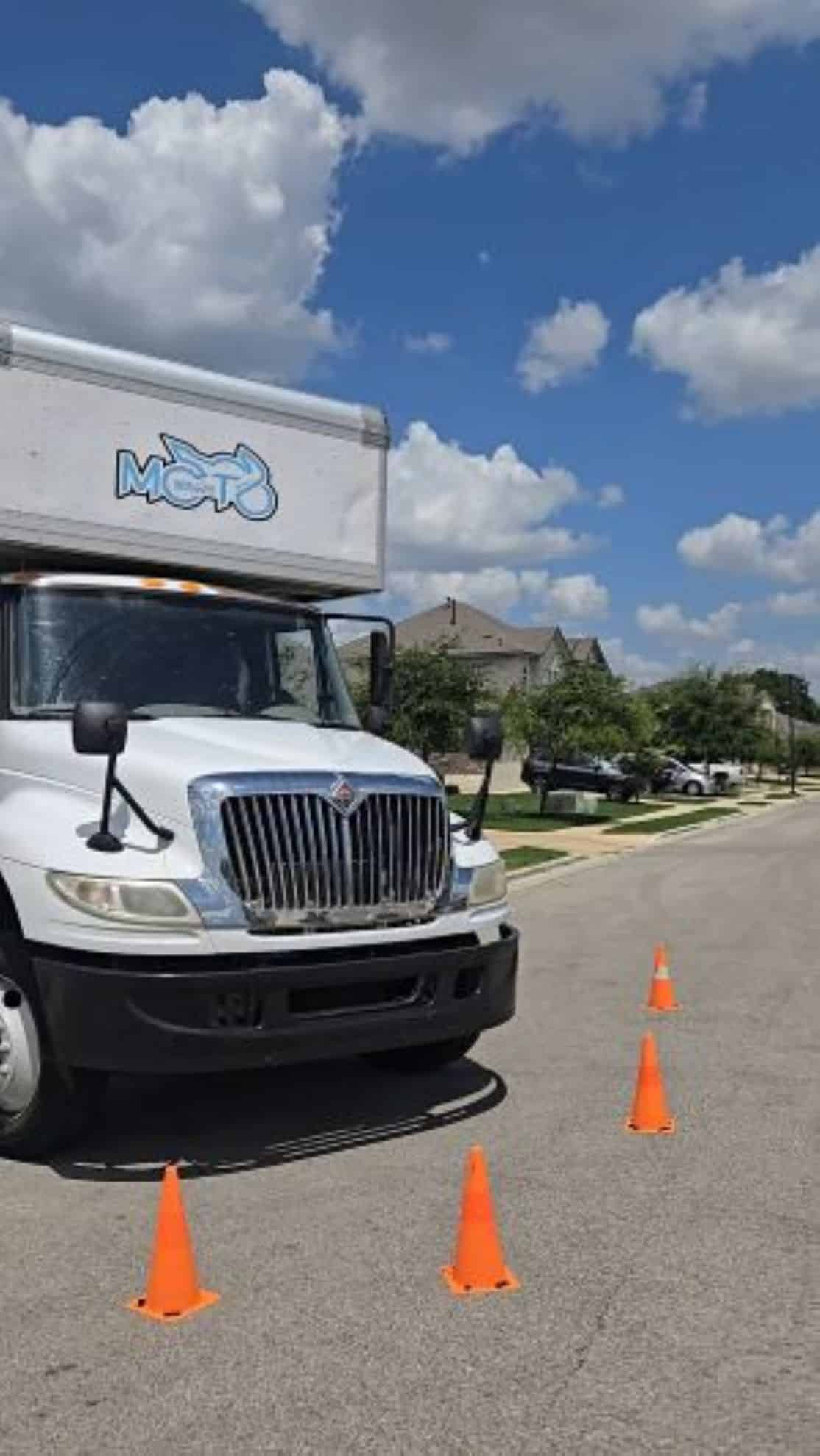Moto Movers Moving truck parked on a suburban Georgetown, TX street with orange traffic cones.