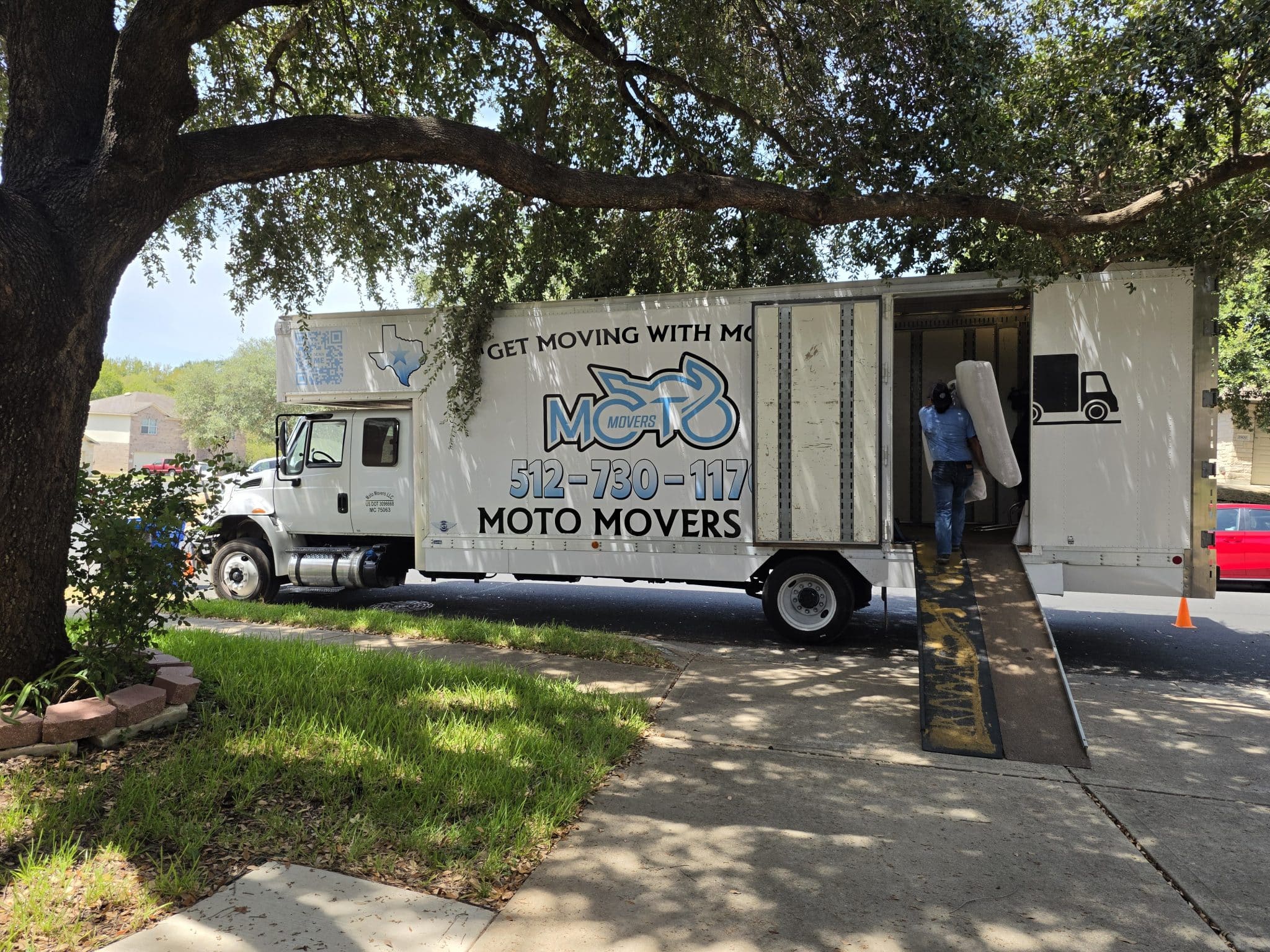 Moto Movers loading Home near Austin, TX Moto Movers truck parked on residential street with a mover carrying furniture near Austin, TX