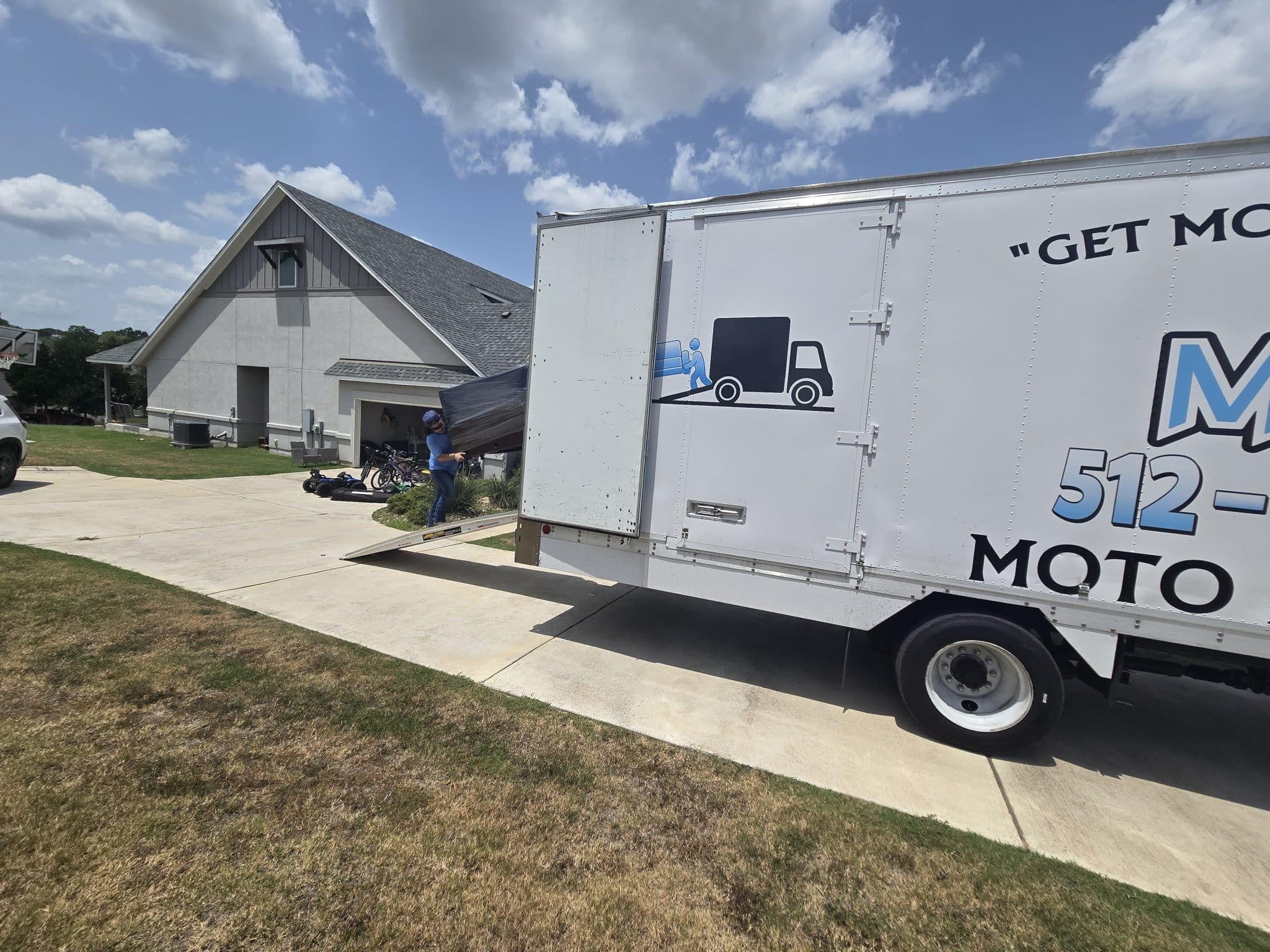 Large Home Loading Moto Movers carrying furniture into a moving truck at a large home in Cedar Creek, Texas.