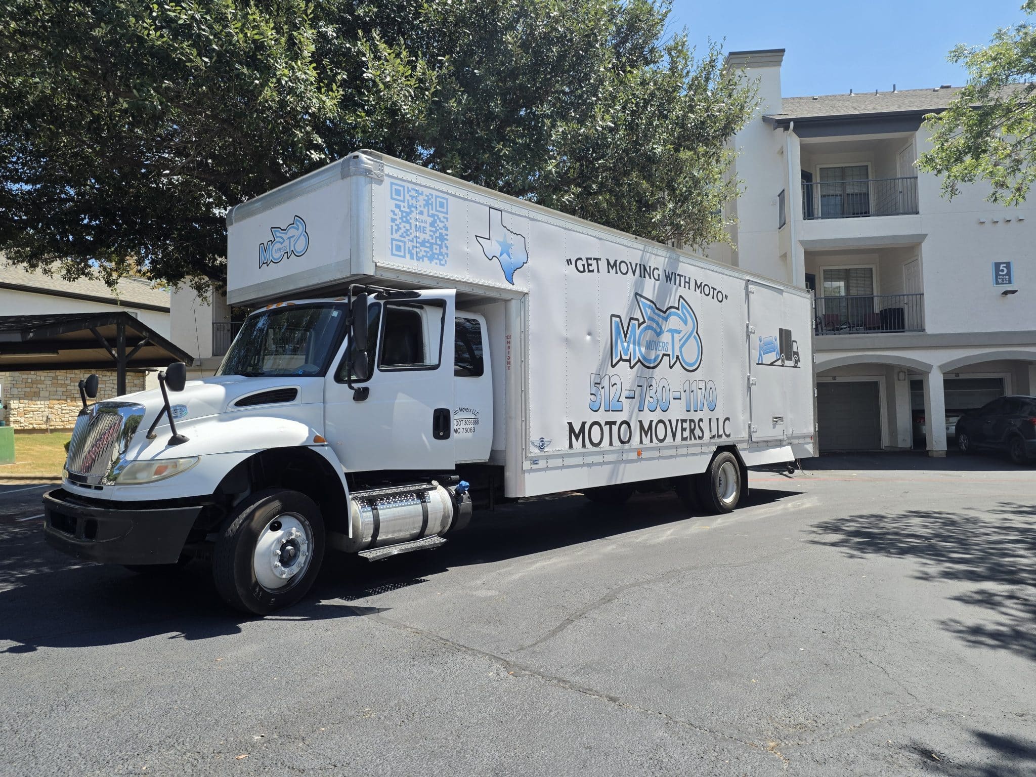 Moto Movers at The Nine on Shoreline Apartments in Austin Texas Moto Movers truck parked in front of residential building on sunny day.