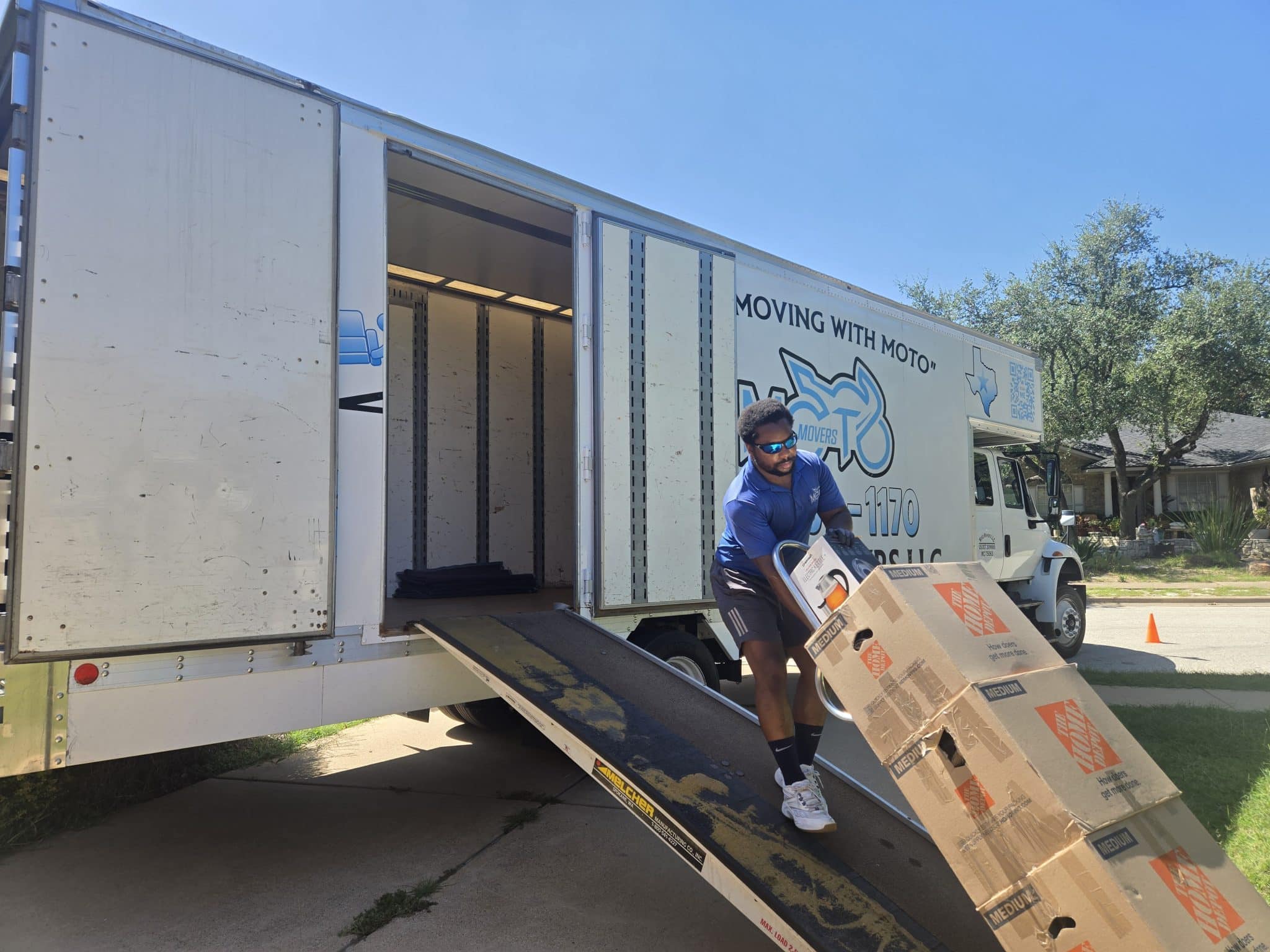 Moto Movers house moving in Austin Texas Moto Movers truck with a mover dollying boxes at a home near Austin, Texas.